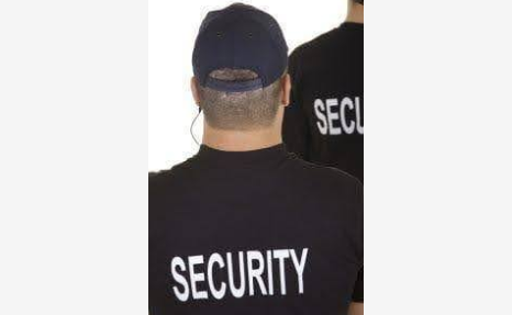 Two men in black shirts with the word security on them.