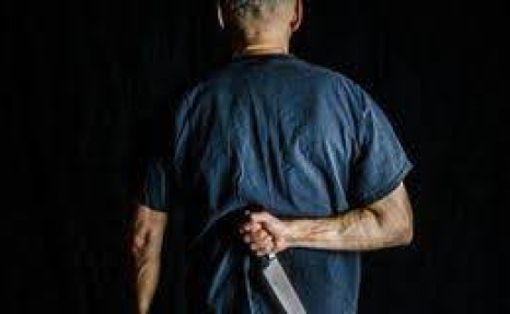 A man in blue shirt holding a knife.