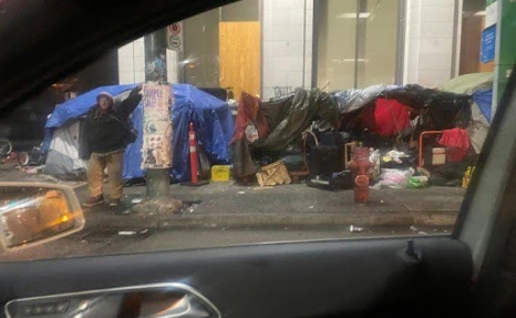 A person standing in front of a building with trash.