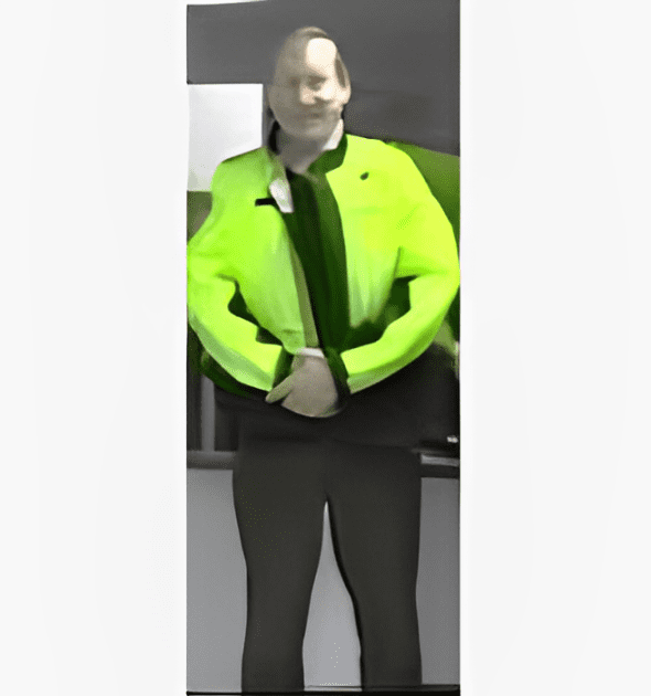 A man in neon yellow jacket standing next to a wall.