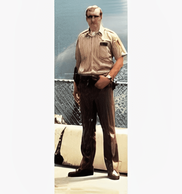 A man in uniform standing on top of a boat.
